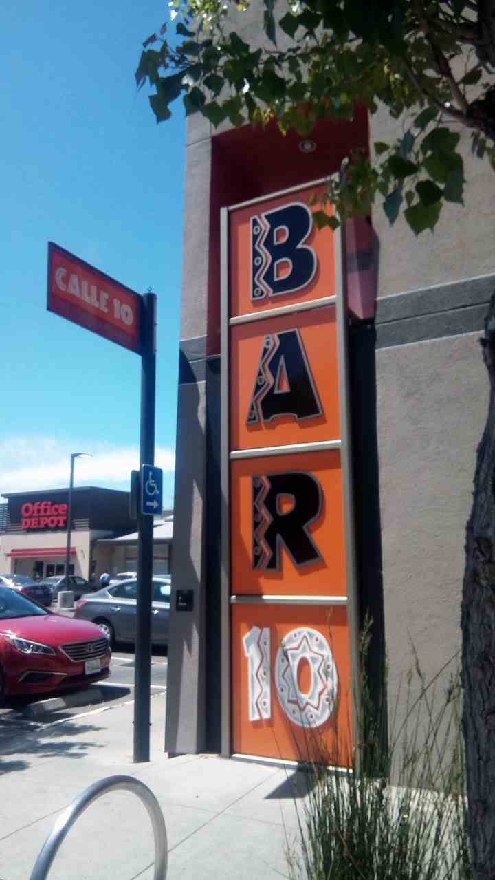 The vertical custom outdoor sign features bright orange panels and bold lettering, making it stand out and enhancing the storefront's appeal.